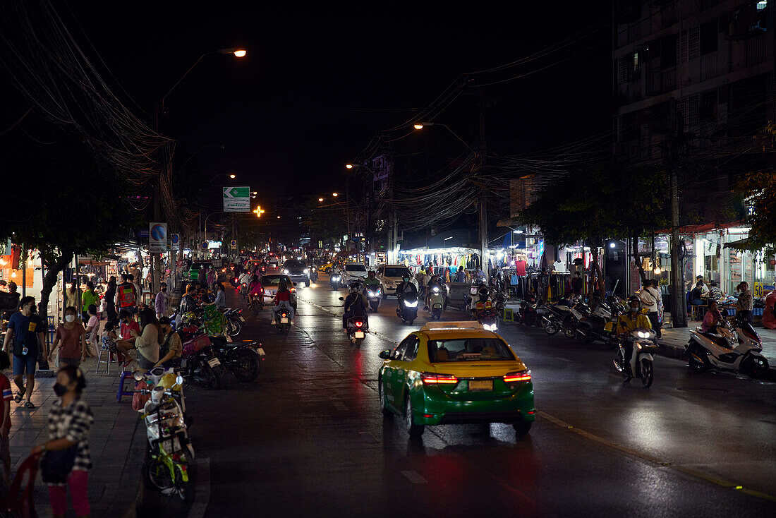 Belebte Straße mit vielen Fußgängern bei Nacht