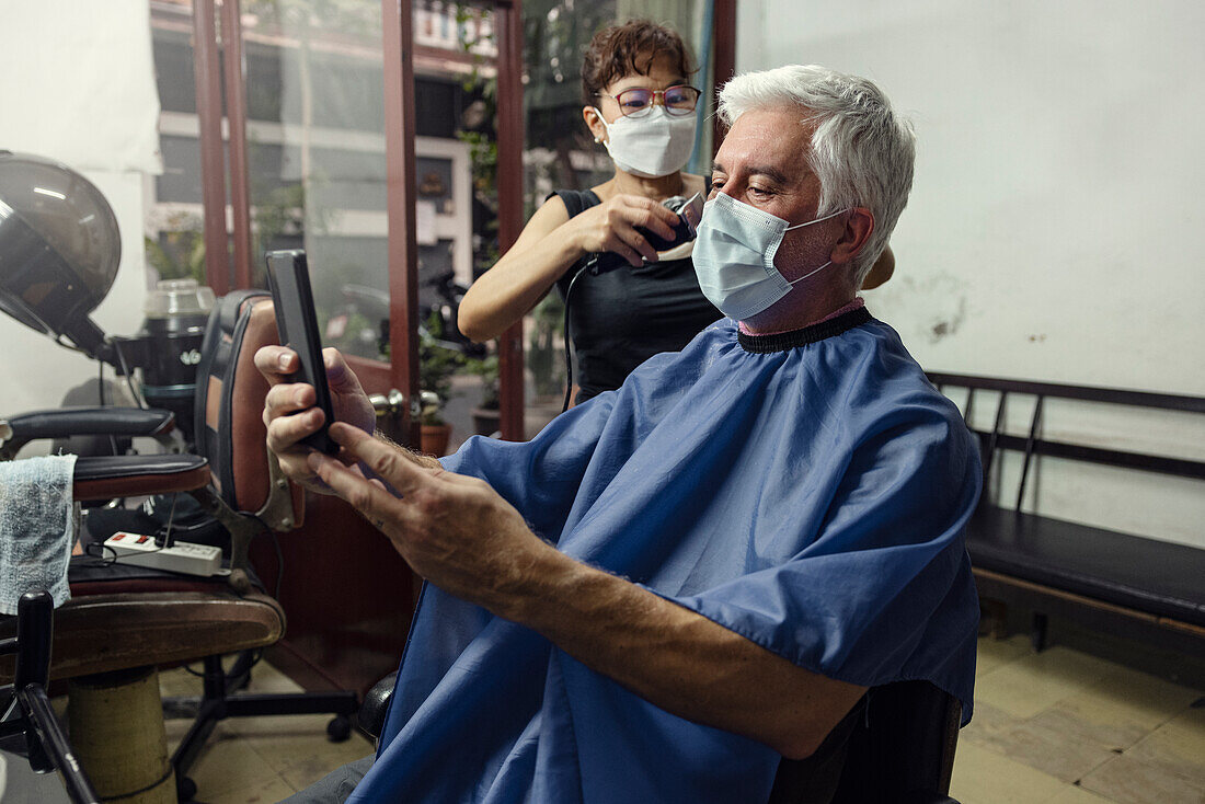 Älterer Mann lässt sich im Friseursalon die Haare schneiden