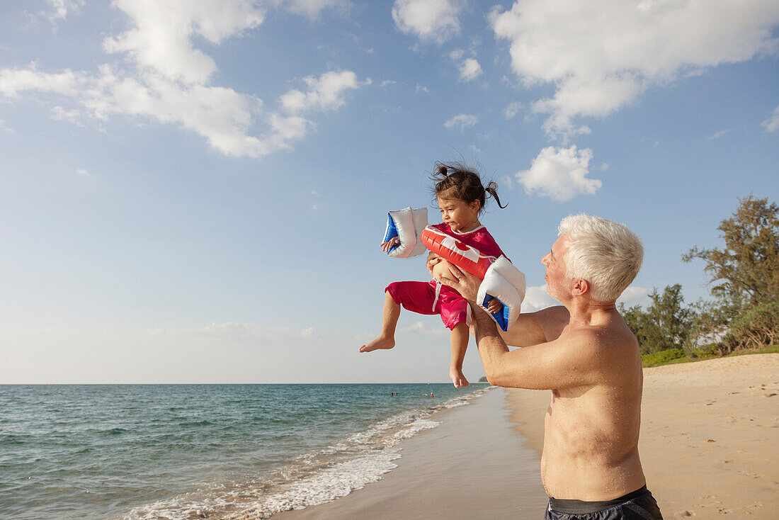 Großvater spielt mit Enkelin am Strand
