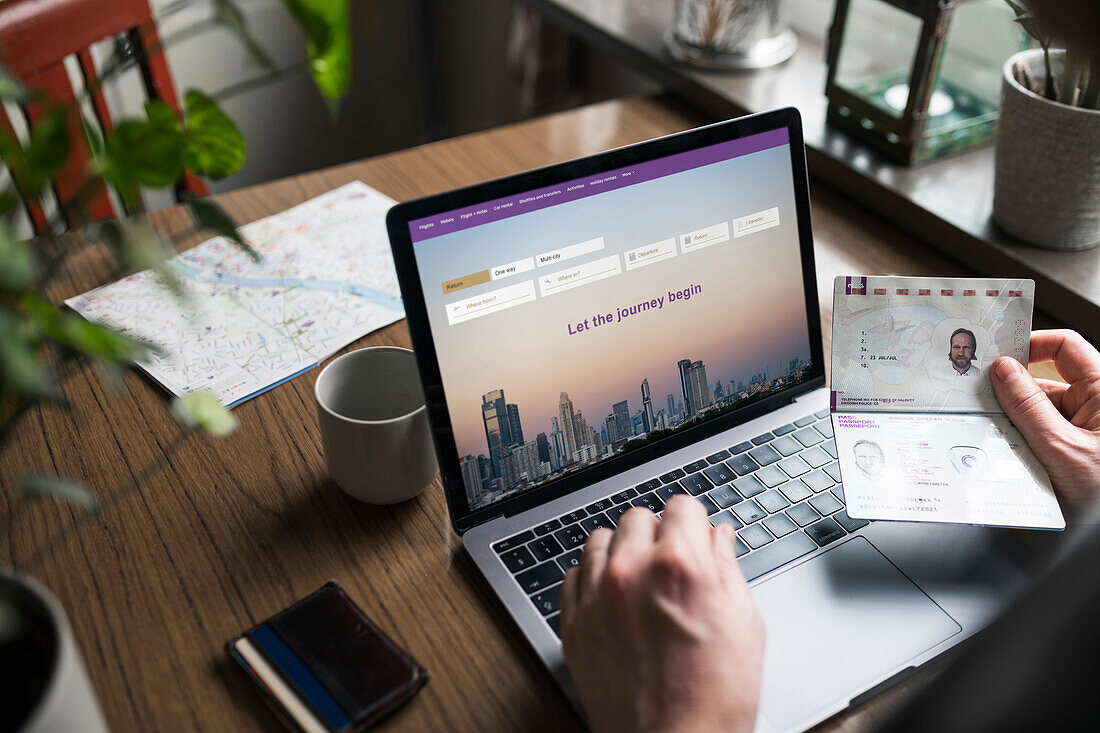 Man searching for flights on laptop and holding passport