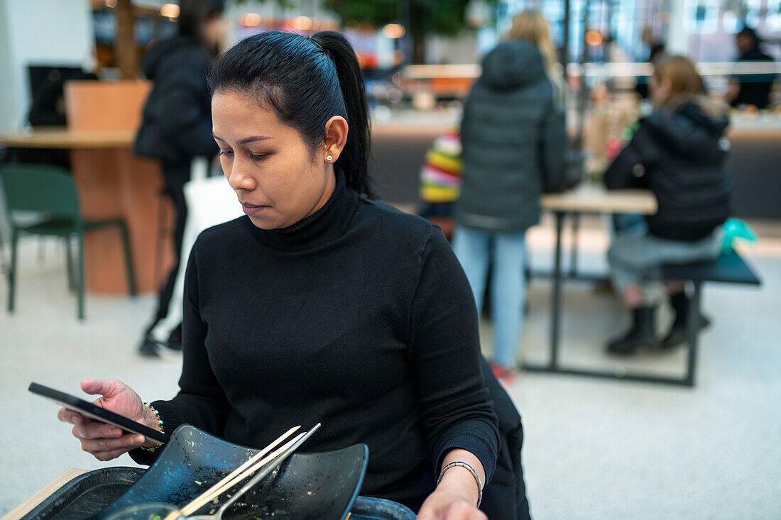 Young woman using smart phone in restaurant