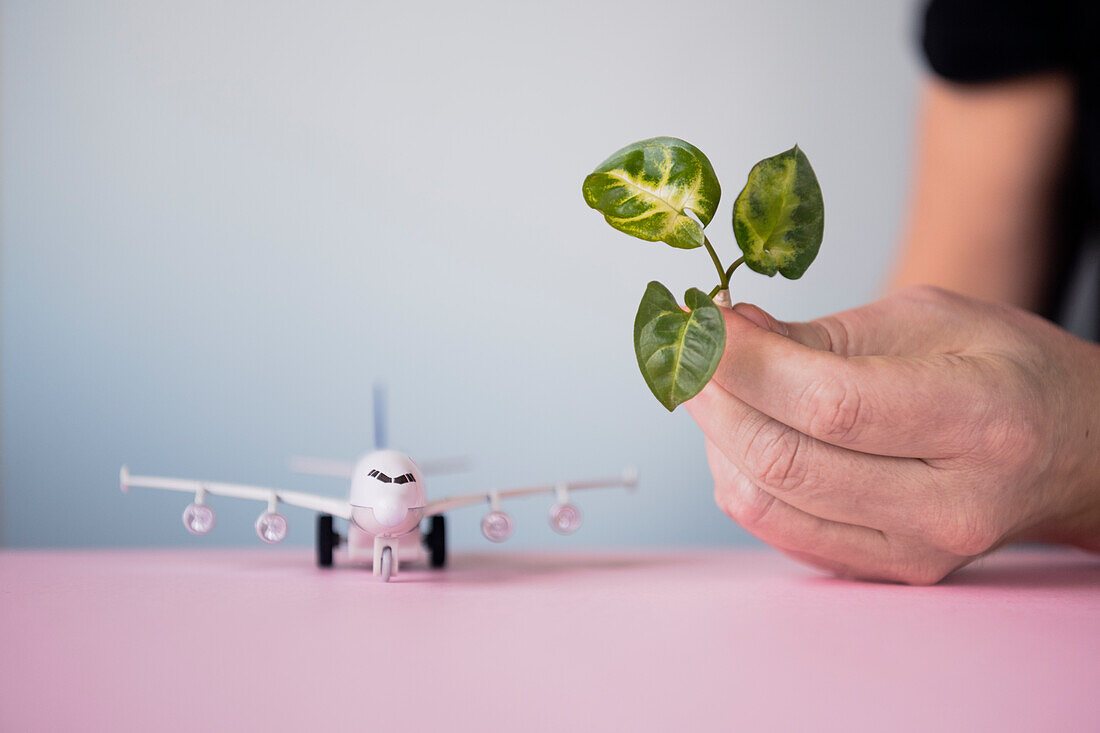 Hand hält Blatt, Flugzeugmodell im Hintergrund