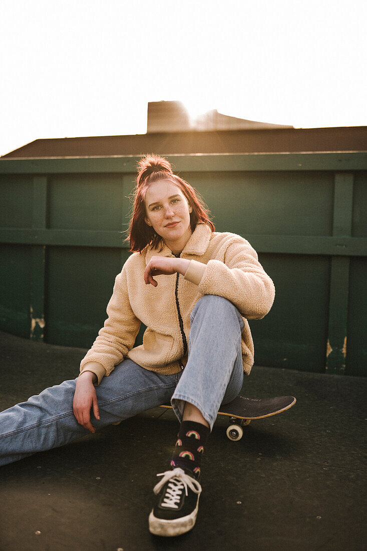 Porträt eines Teenager-Mädchens auf dem Skateboard sitzend