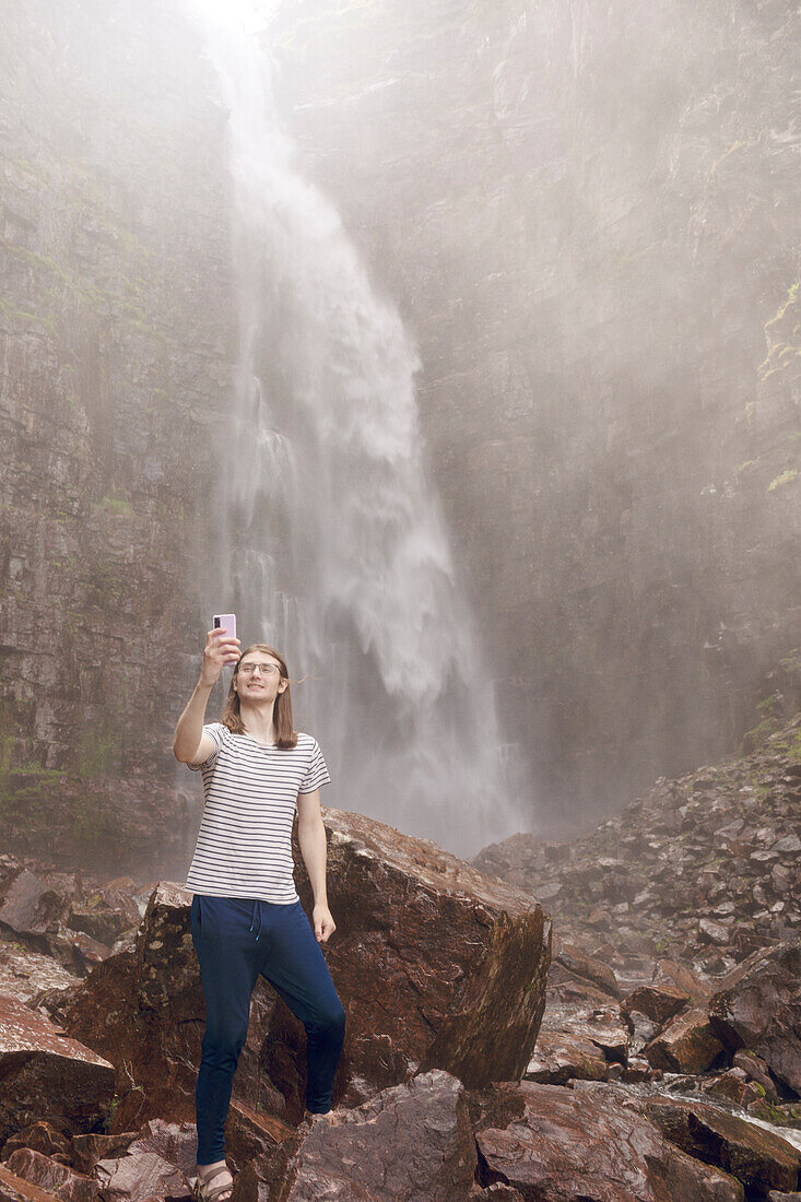 Man taking selfie in front of waterfall