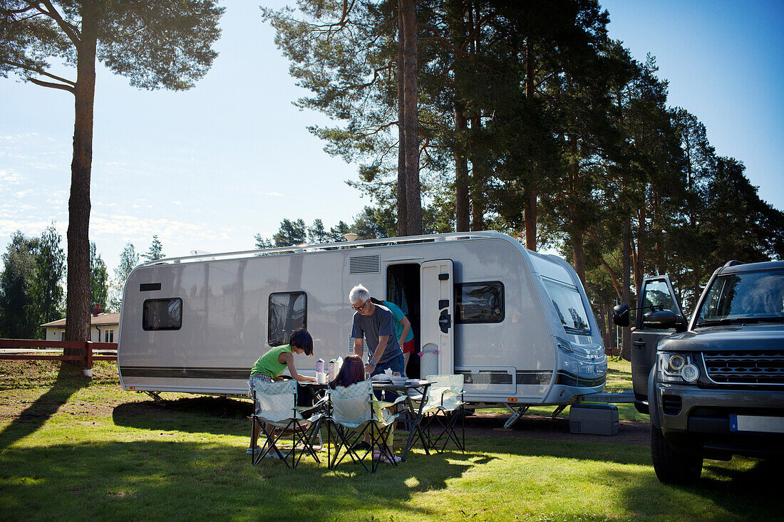 Family having meal in front of camper trailer