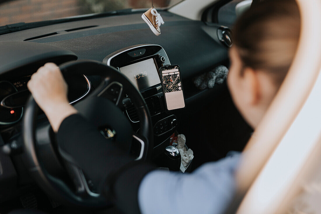 Frau sitzt im Auto und benutzt eine Karte auf dem Telefon