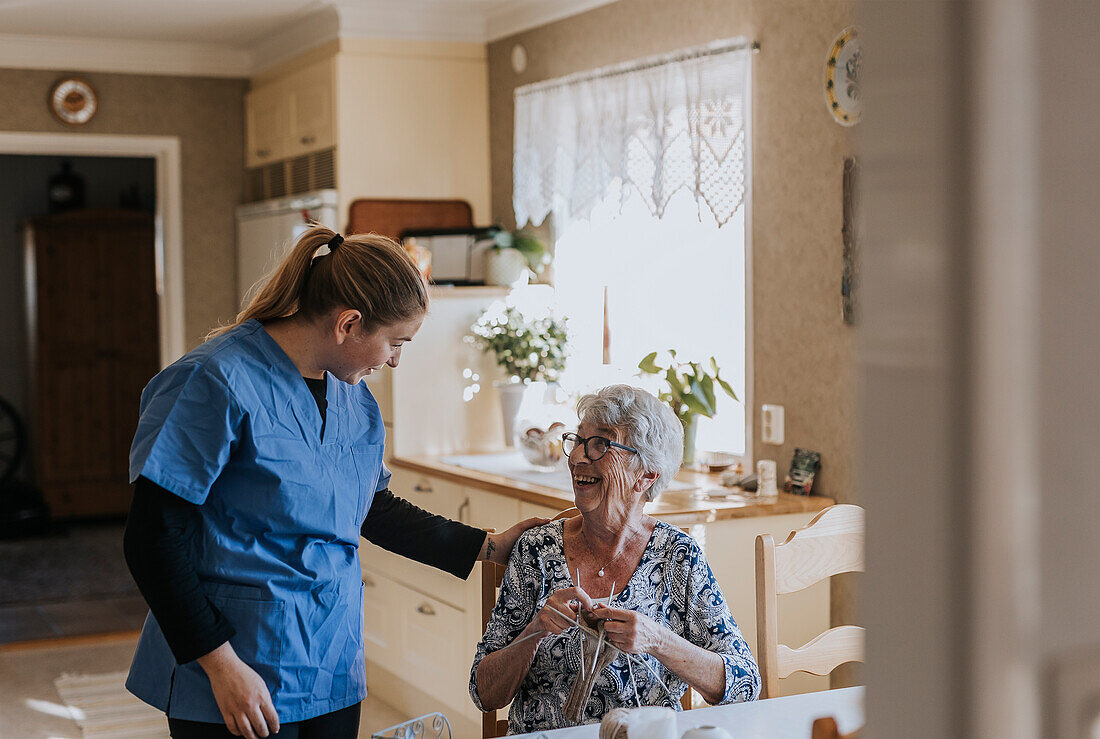 Smiling home caretaker and senior woman at home