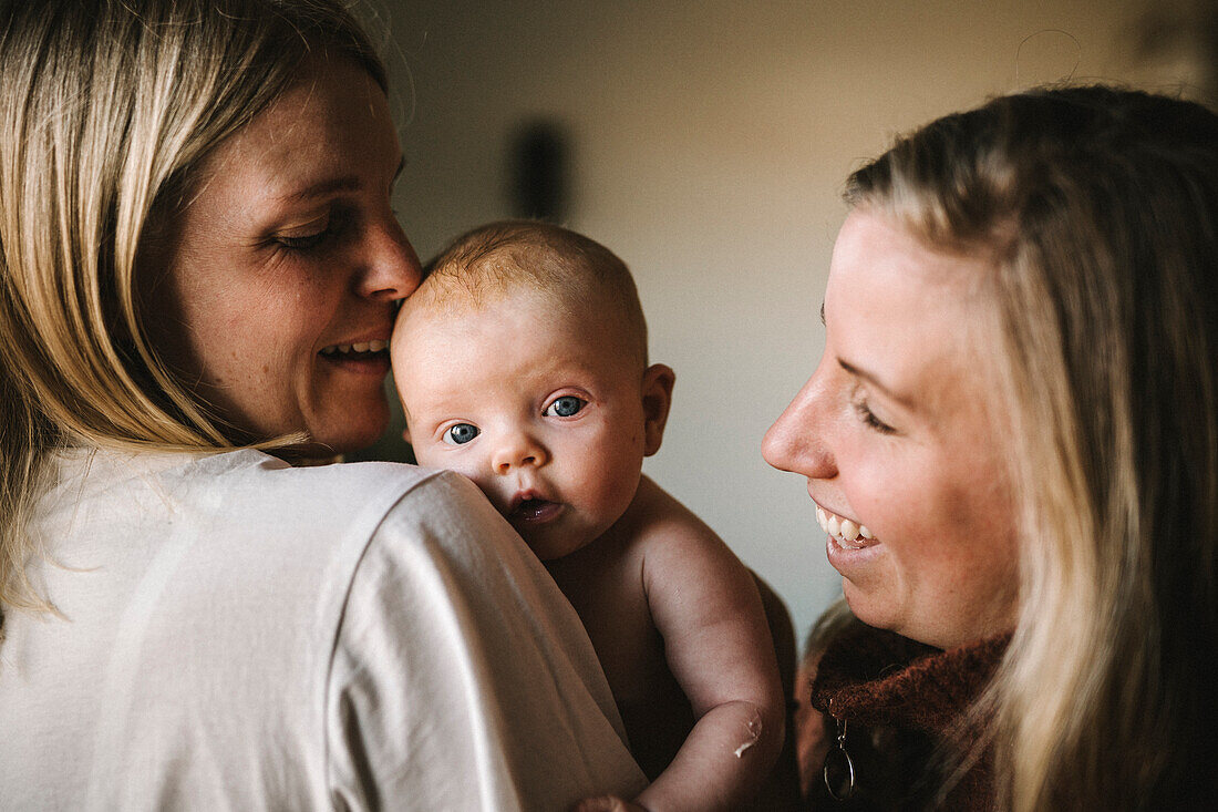 Lächelnde Mütter halten neugeborenes Baby