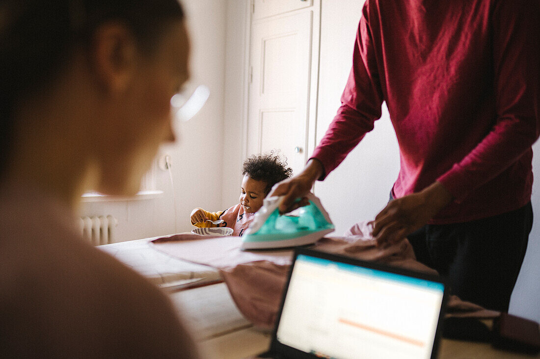 Familie mit Tochter, die zu Hause arbeitet und Hausarbeiten erledigt