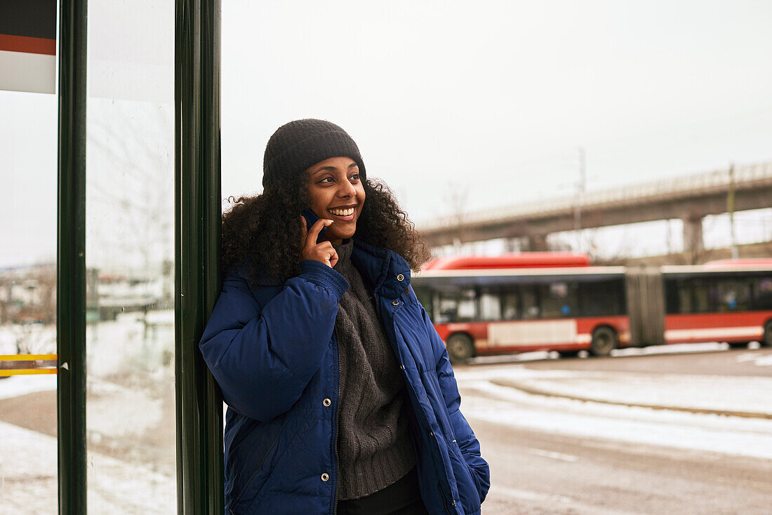 Woman talking via cell phone at bus stop