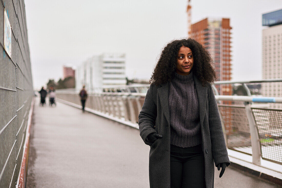 Smiling woman standing on footbridge