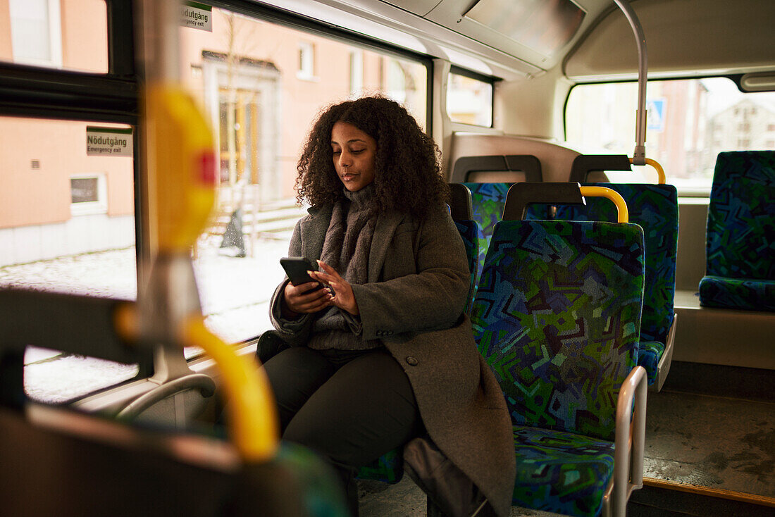 Woman in bus using cell phone