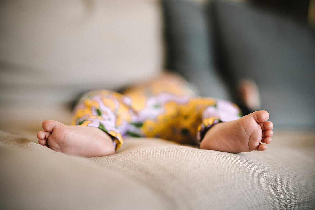 Nackte Füße eines neugeborenen Babys auf dem Sofa