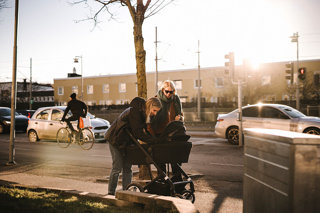 Mothers walking with baby stroller along street