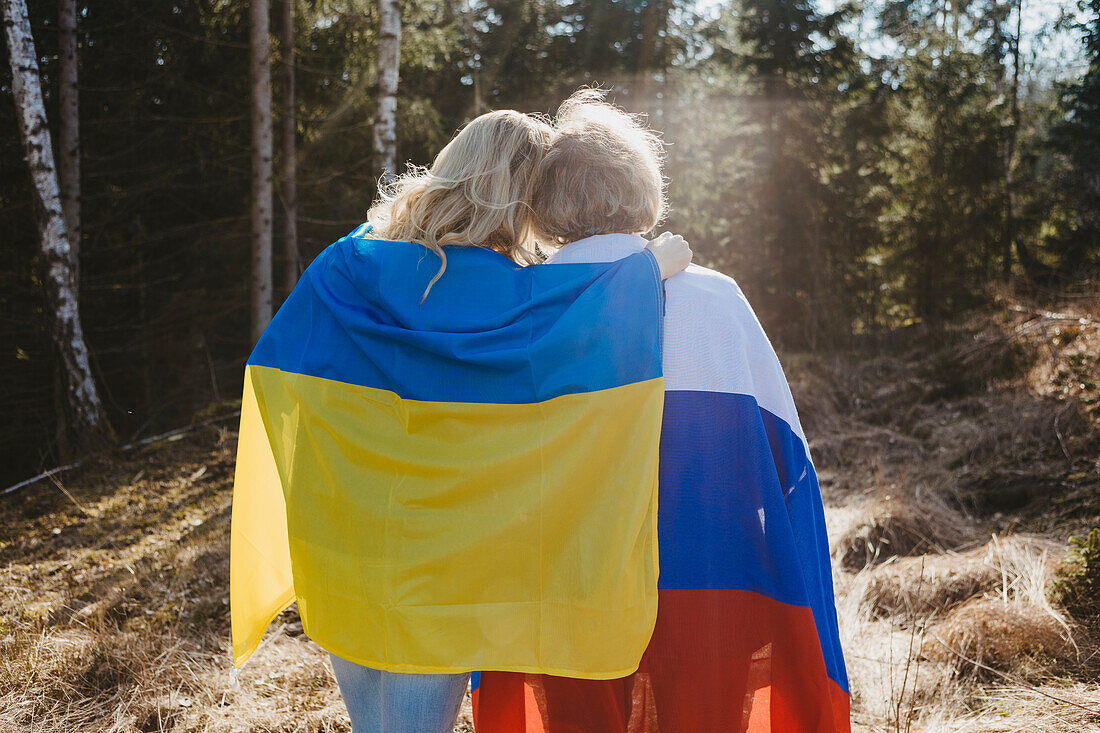 Rear view of women wrapped in Ukrainian and Russian flags