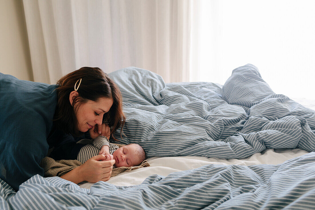 Mother cuddling newborn baby in bed