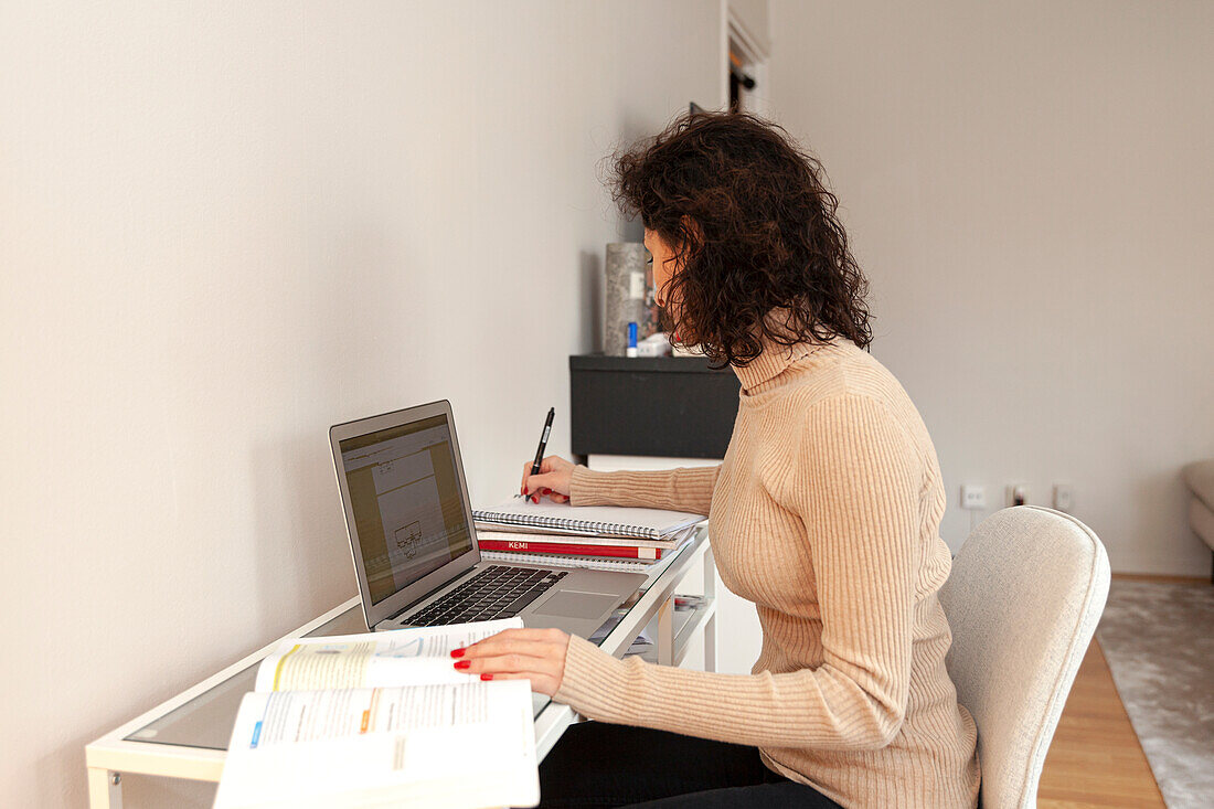 Junge Frau arbeitet zu Hause am Schreibtisch
