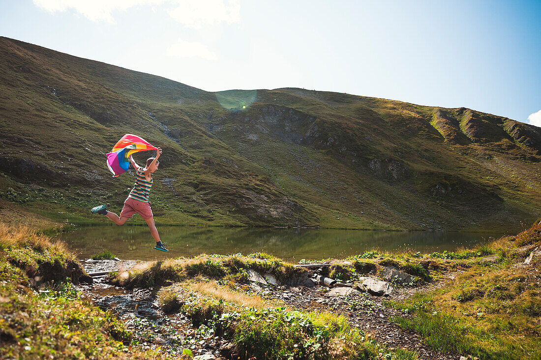 Man with LGBTIQ Community flag in mountains