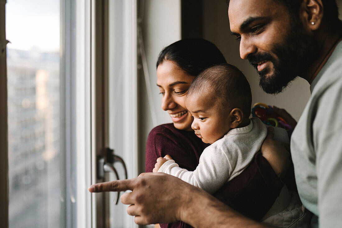 Father and mother with baby looking through window