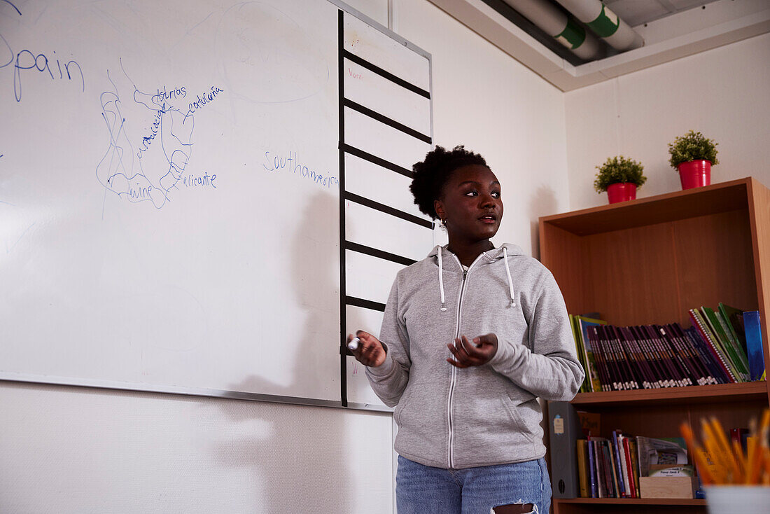 Teenage girl standing in front of whiteboard in classroom