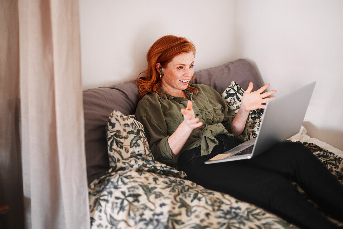 Smiling woman using laptop on bed