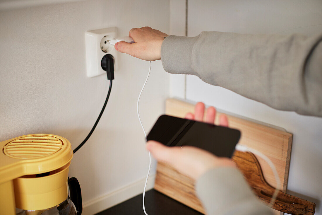 Hands plugging in cell phone charger