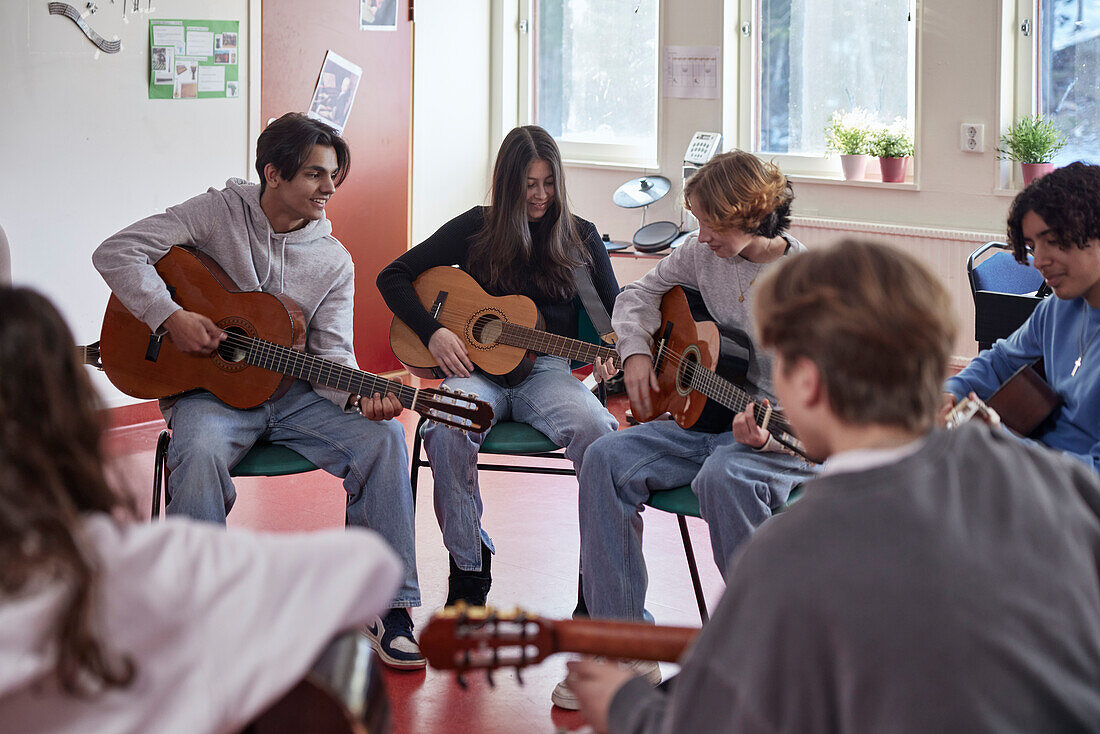 Teenagers attending guitar lesson