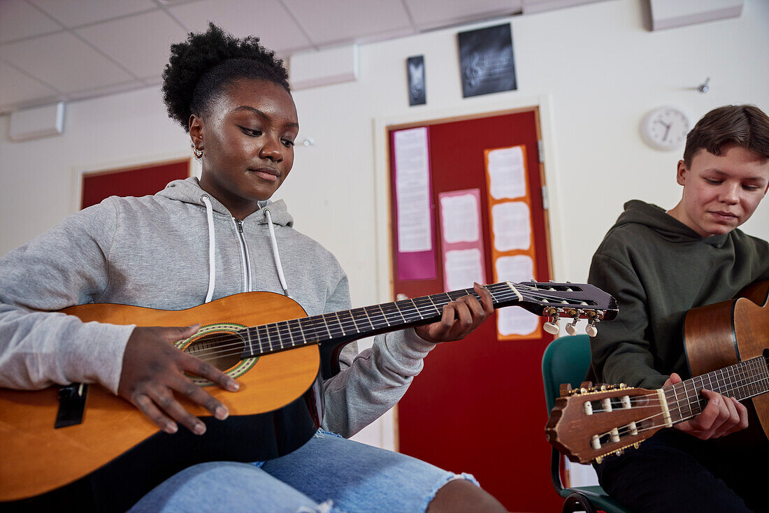 Teenagers attending guitar lesson