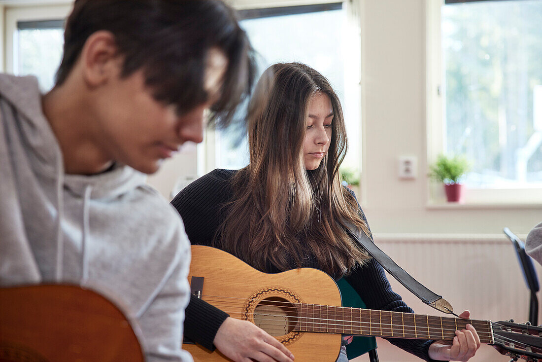 Teenager beim Gitarrenunterricht