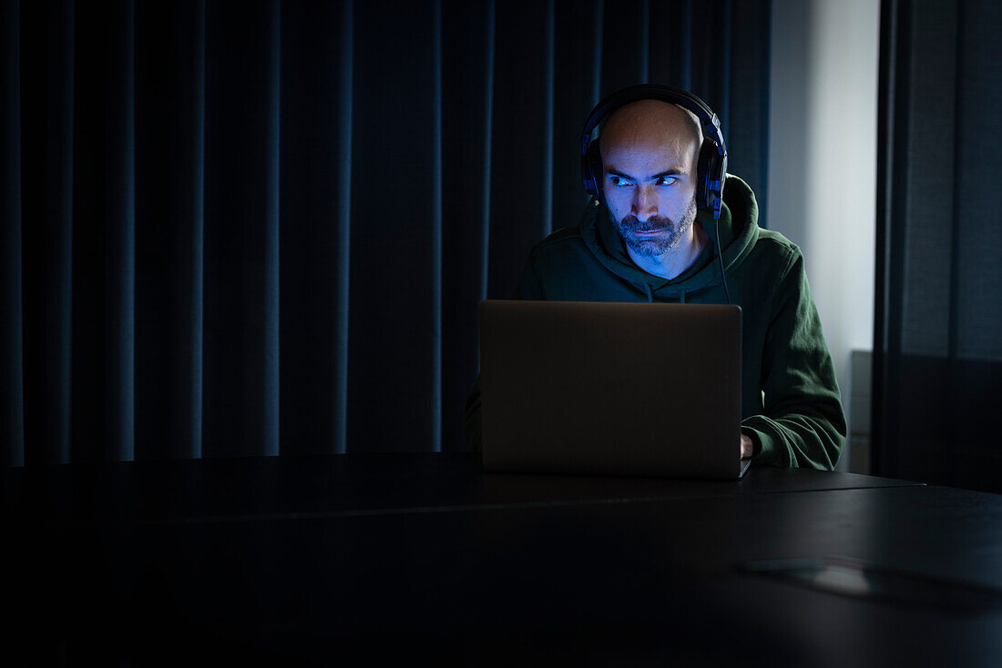 Man working on laptop in dark office