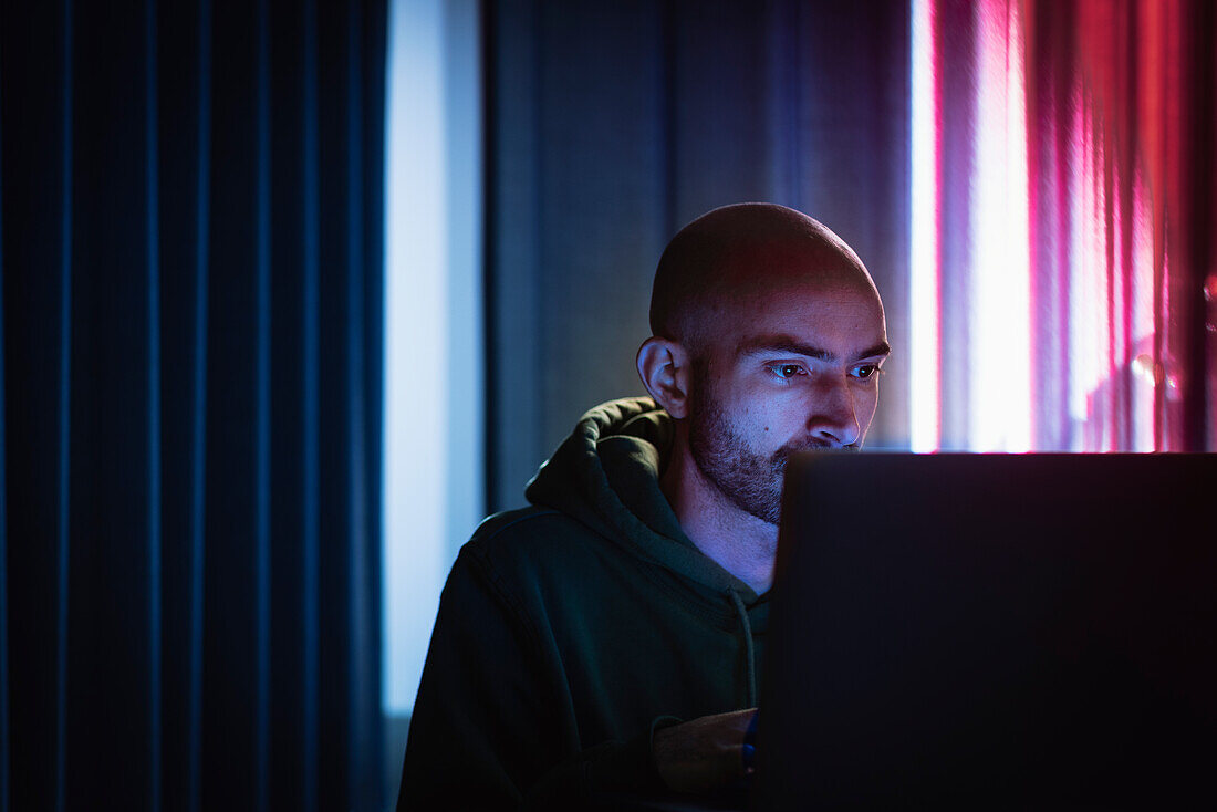 Man working on laptop in dark office