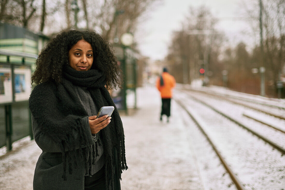 Woman at train station platform using cell phone