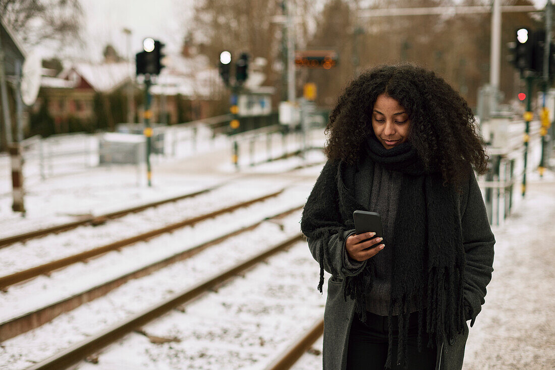 Woman at train station platform using cell phone