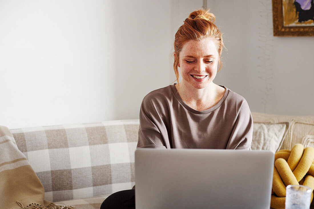 Lächelnde Frau benutzt Laptop zu Hause