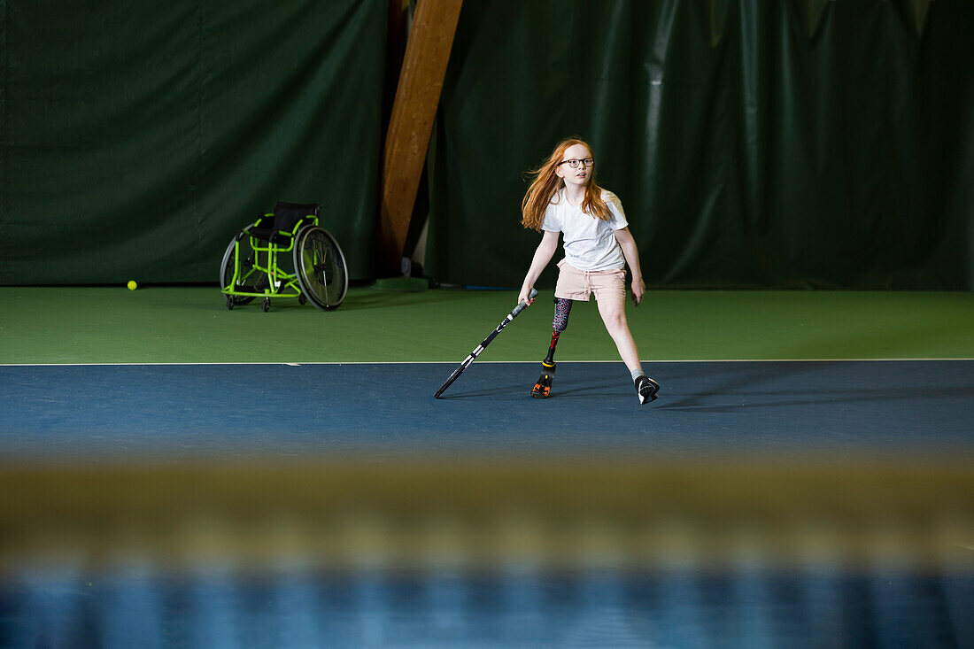 Mädchen mit Beinprothese beim Tennisspielen