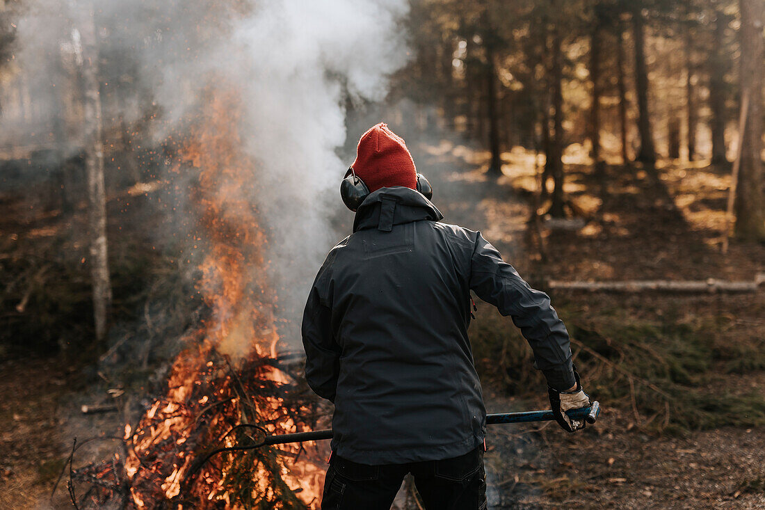 Rückansicht einer Person, die Äste im Wald verbrennt