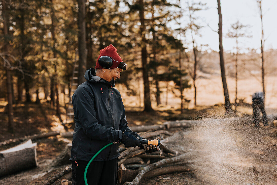 Frau mit Wasserschlauch im Wald