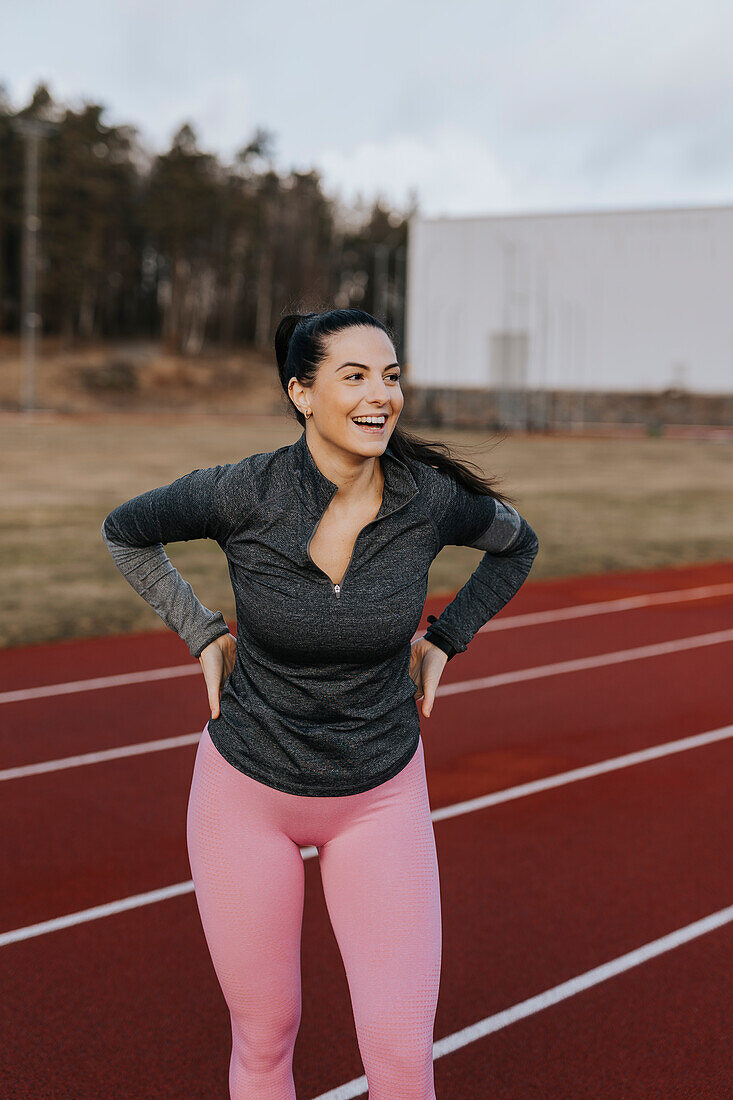 Happy woman standing at running track