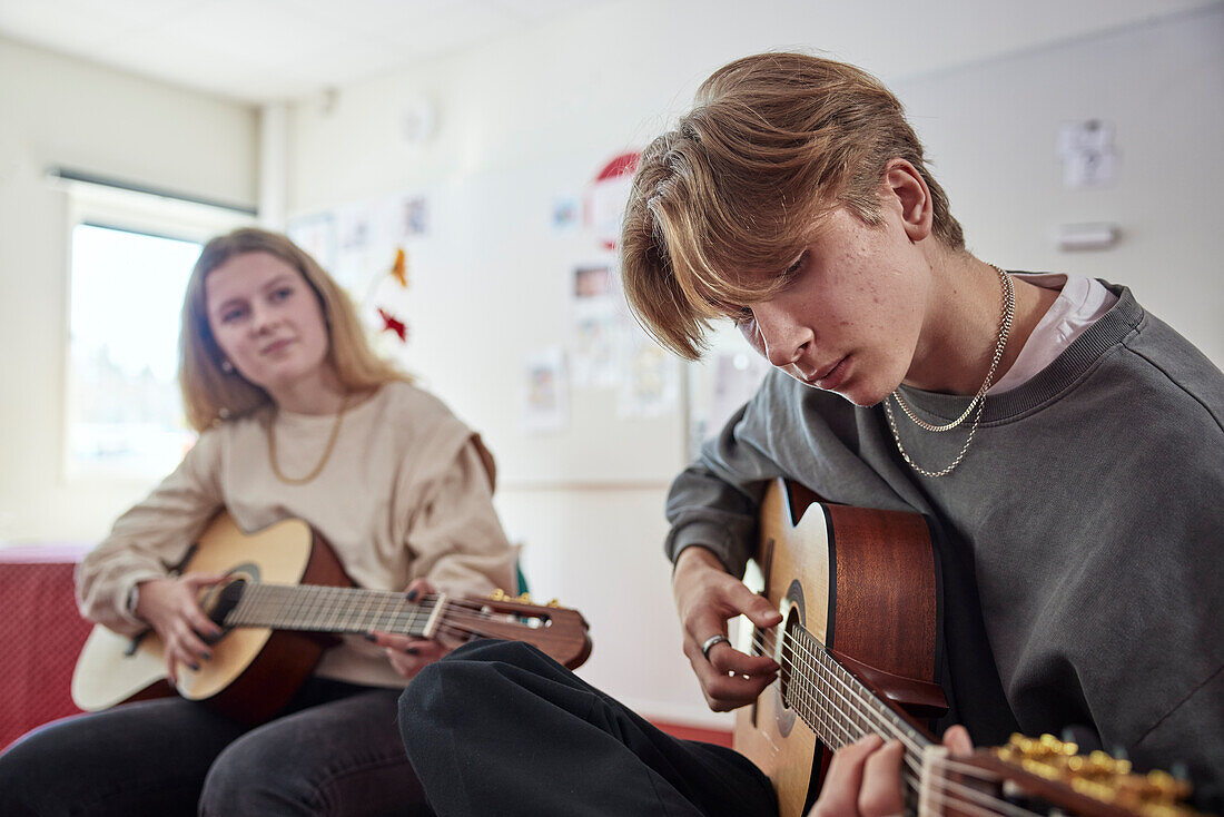 Teenagers attending guitar lesson