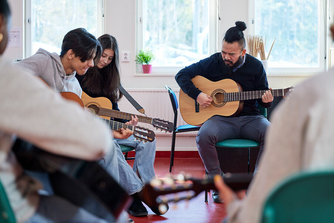 Teenagers attending guitar lesson