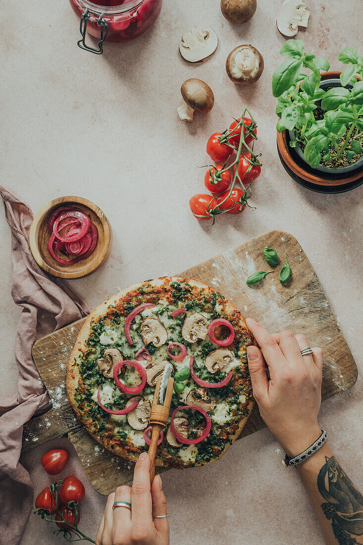 Hands cutting homemade pizza