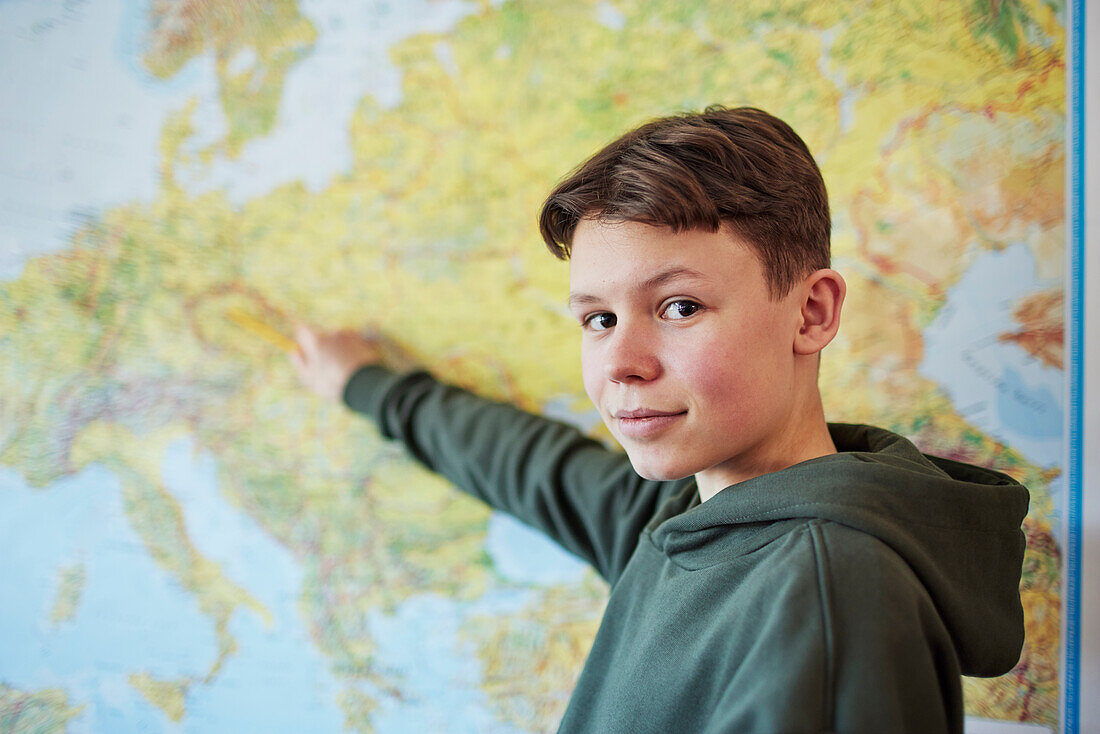 Porträt eines Jungen, der in der Klasse auf eine Karte zeigt