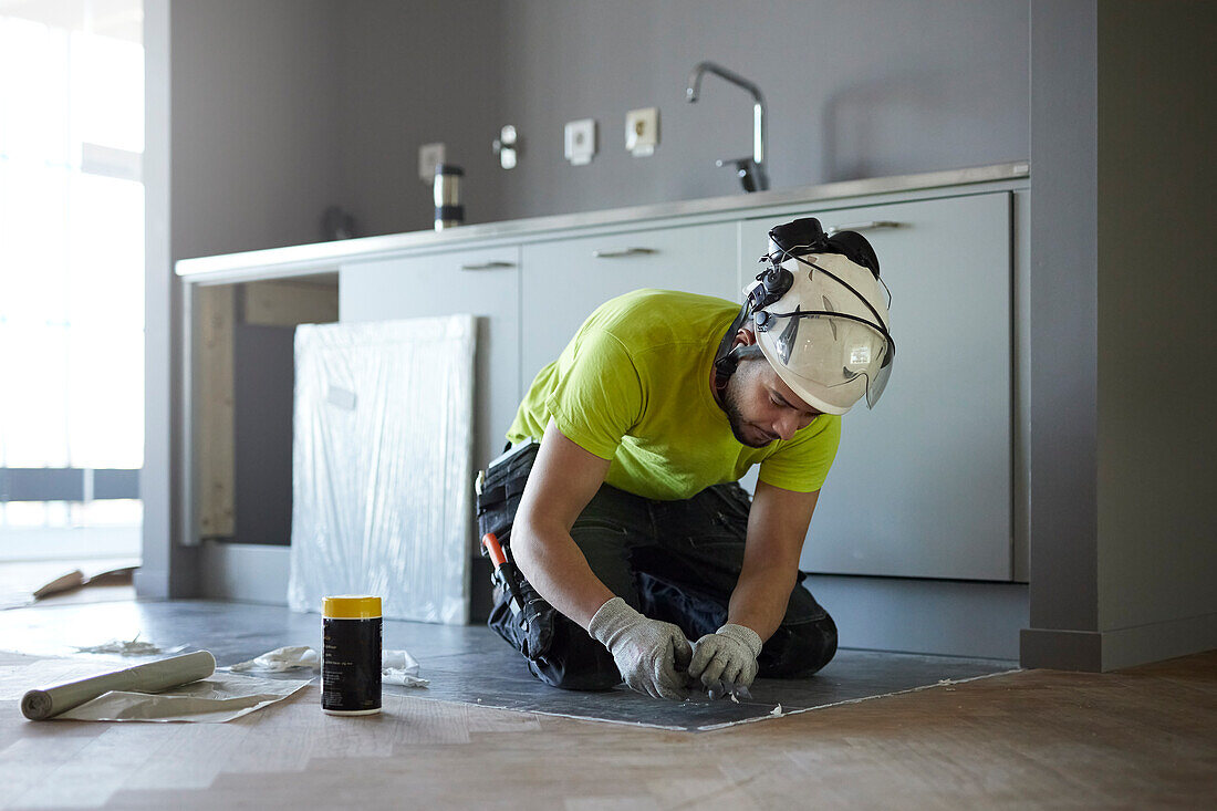 Arbeiter beim Verlegen eines Fußbodens in der Küche