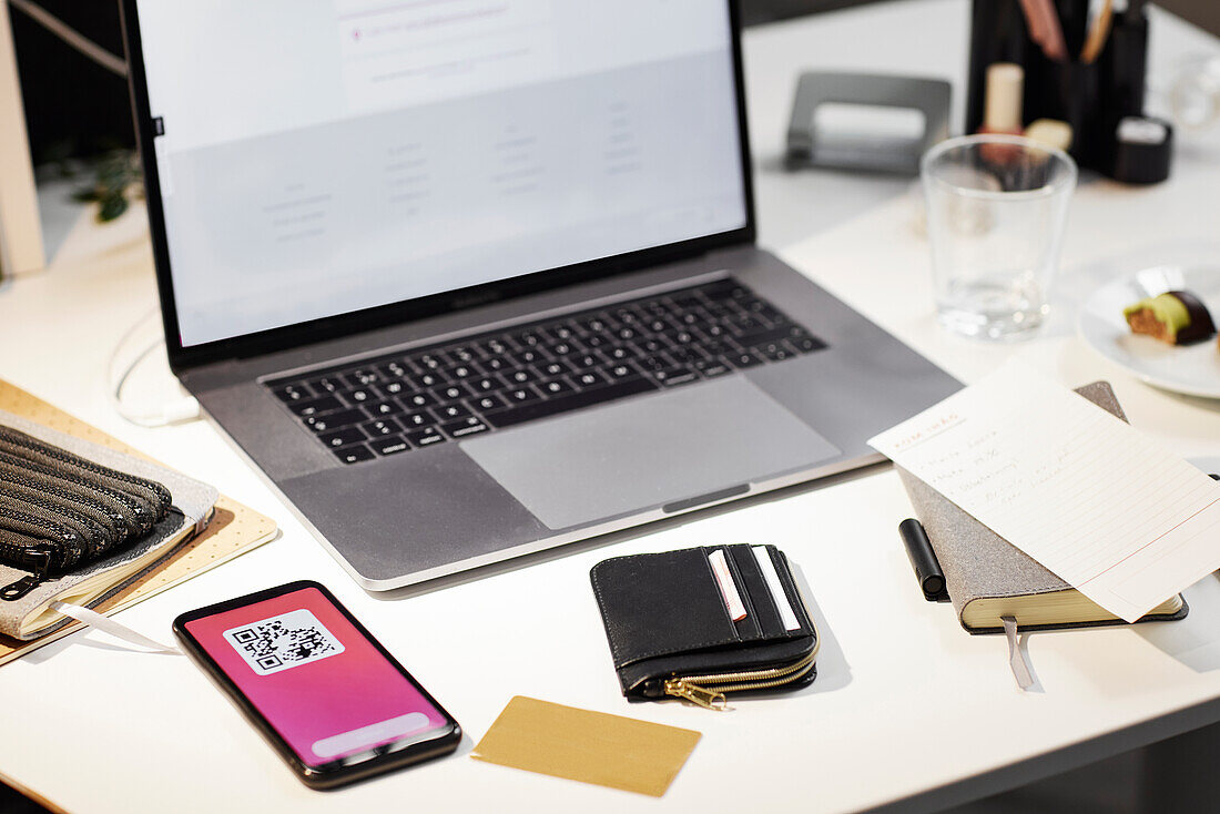Blick auf den Schreibtisch mit Laptop, Handy und Kreditkarte