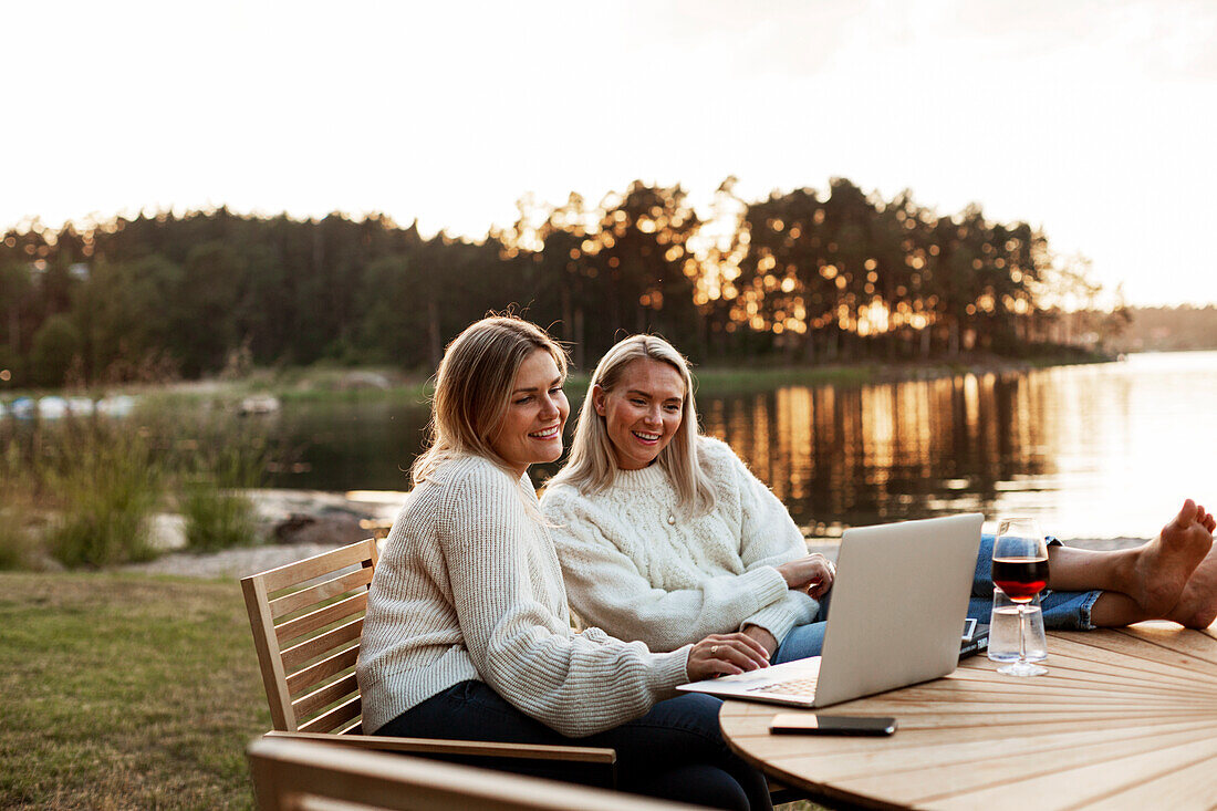 Women using laptop at lake