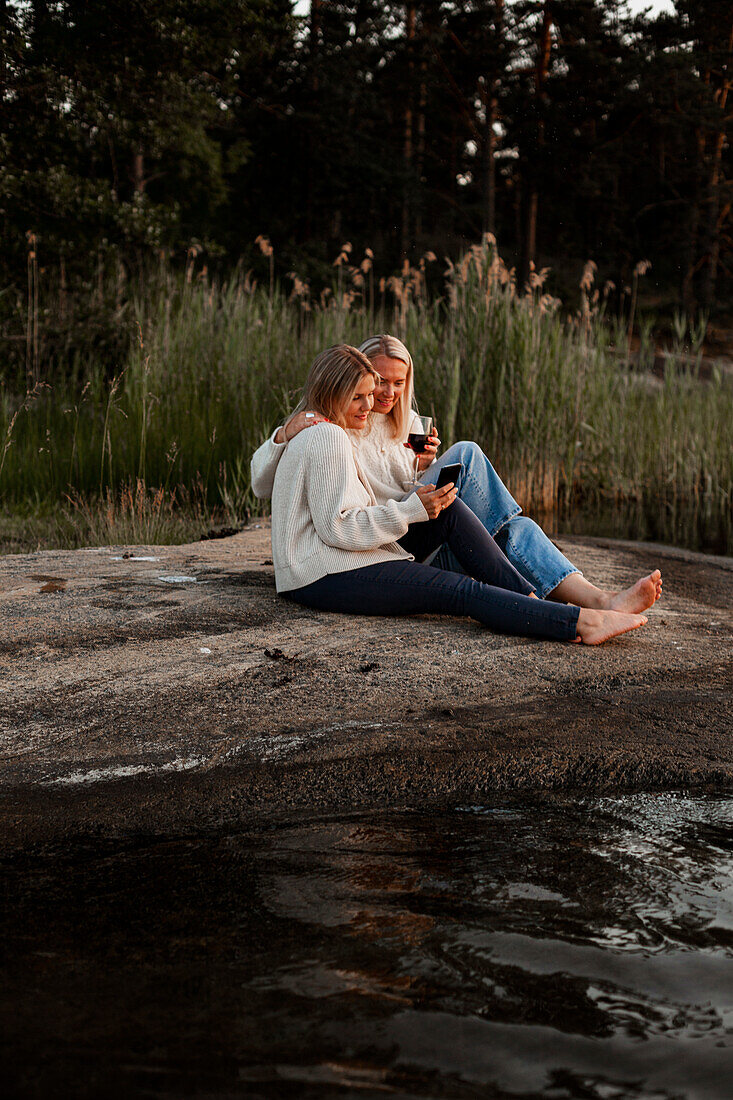 Female couple sitting at lake