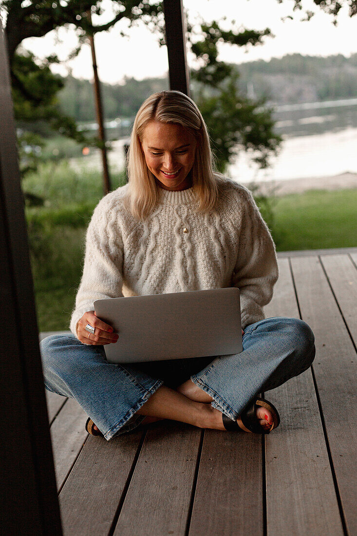 Frau mit Laptop auf der Veranda