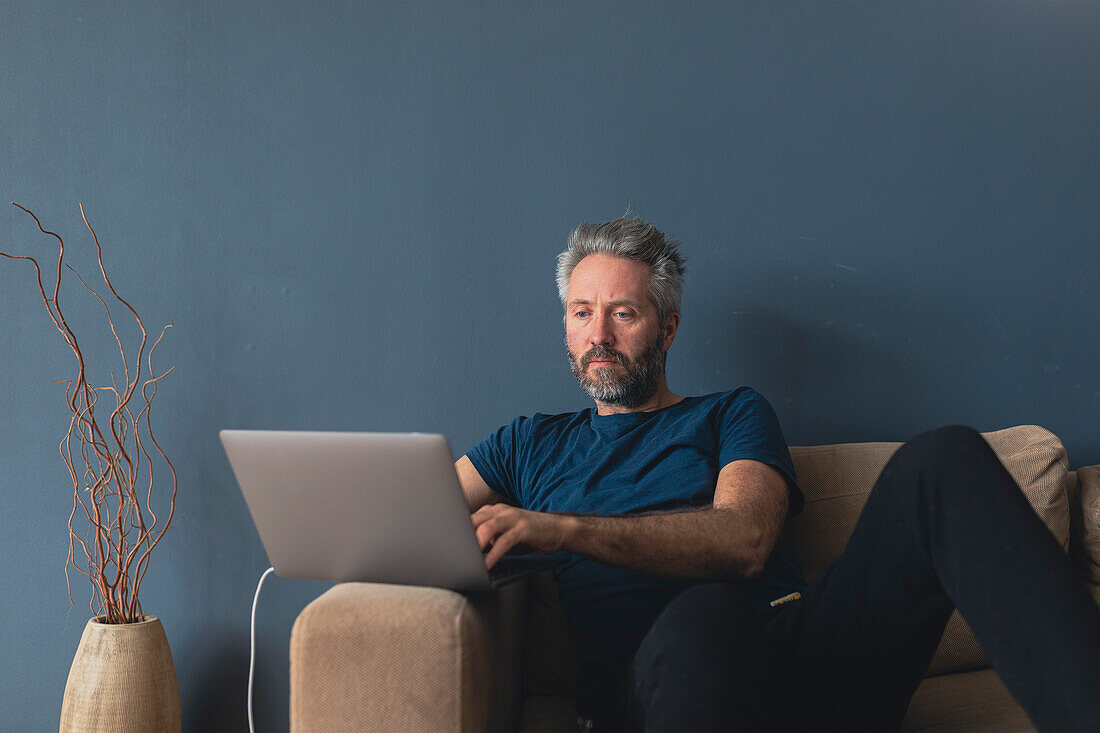 Man with laptop sitting on sofa