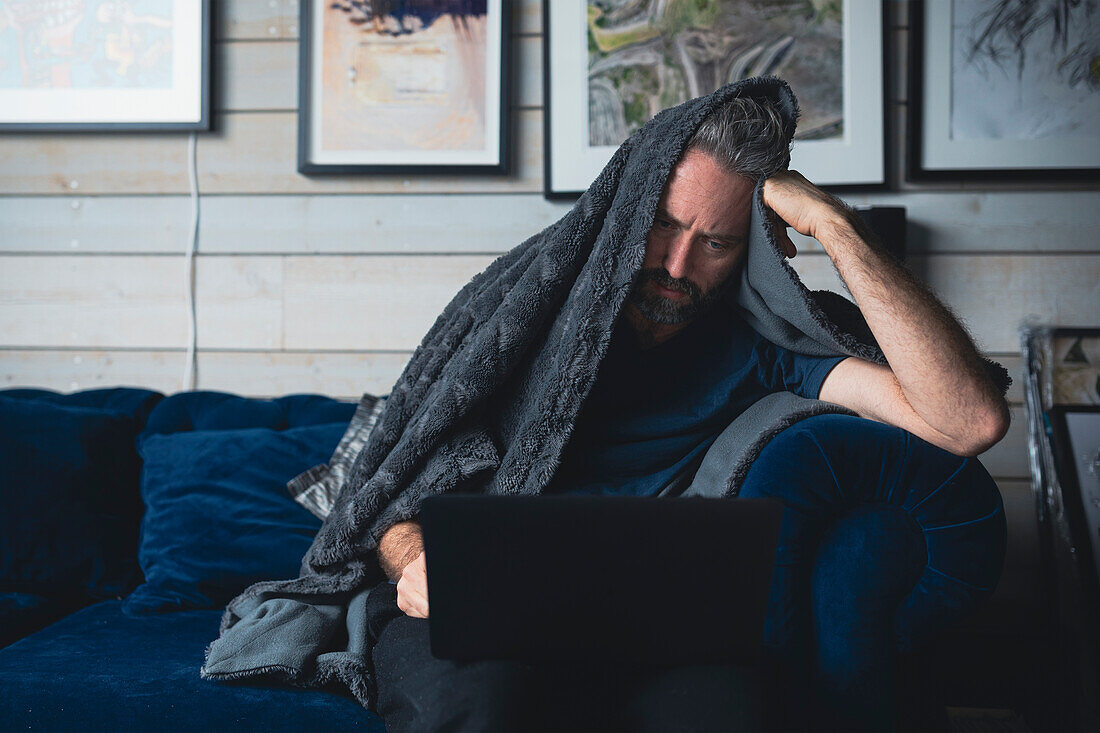 Man with laptop sitting on sofa