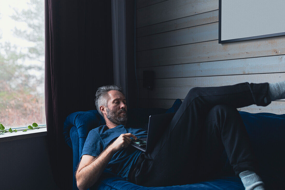 Mann mit Laptop auf Sofa sitzend